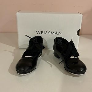 Little girl’s black patent leather tap shoes.